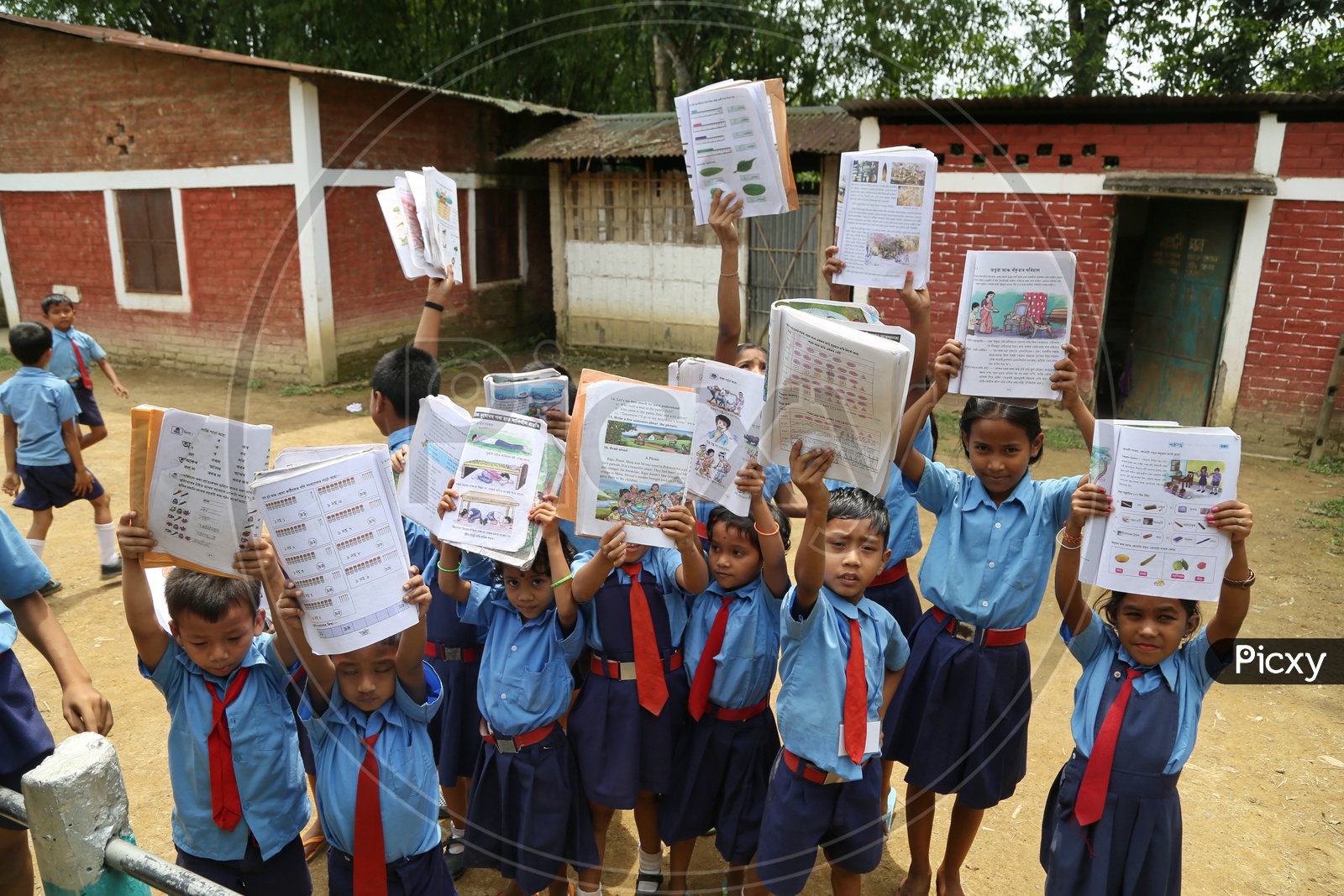 School children Or  School Students Wearing Uniforms And Holding Books In Hand   in a Rural Village School Compound Or Premise