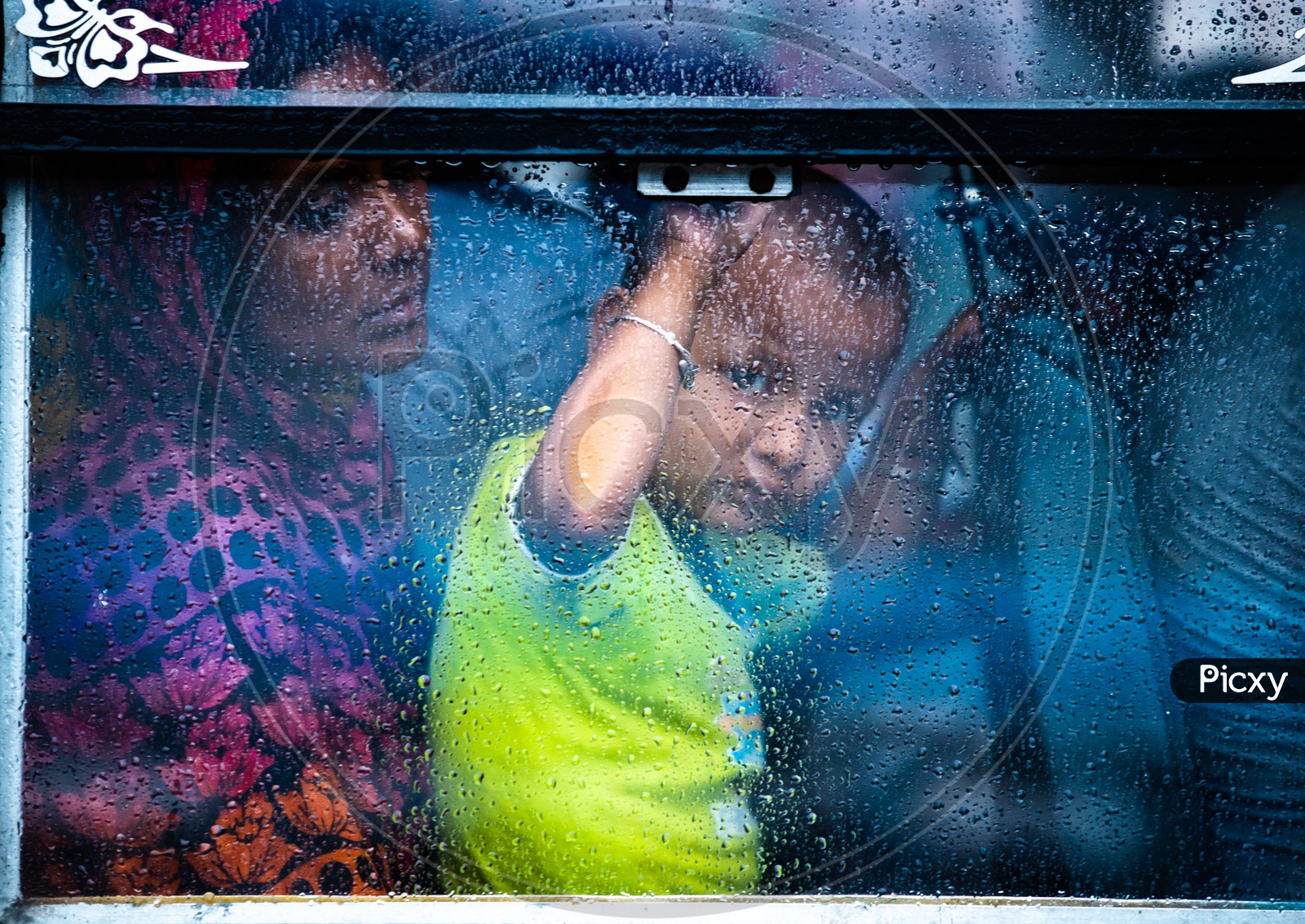 A Small  Child Looking Through The  Window Glass Of a   Bus While The  Rain Lashing Outside