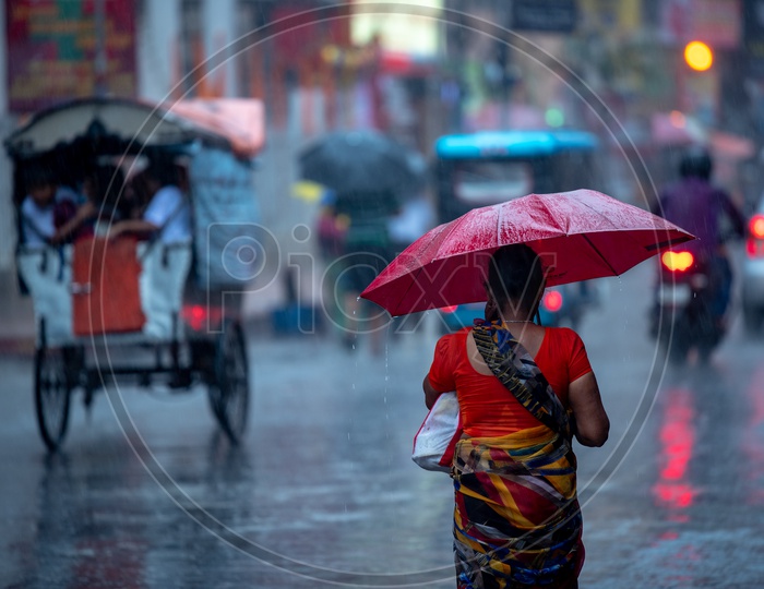 An Woman Holding  a  Umbrella In Hand  and Walking On The Streets  in Heavy Rain In Kolkata