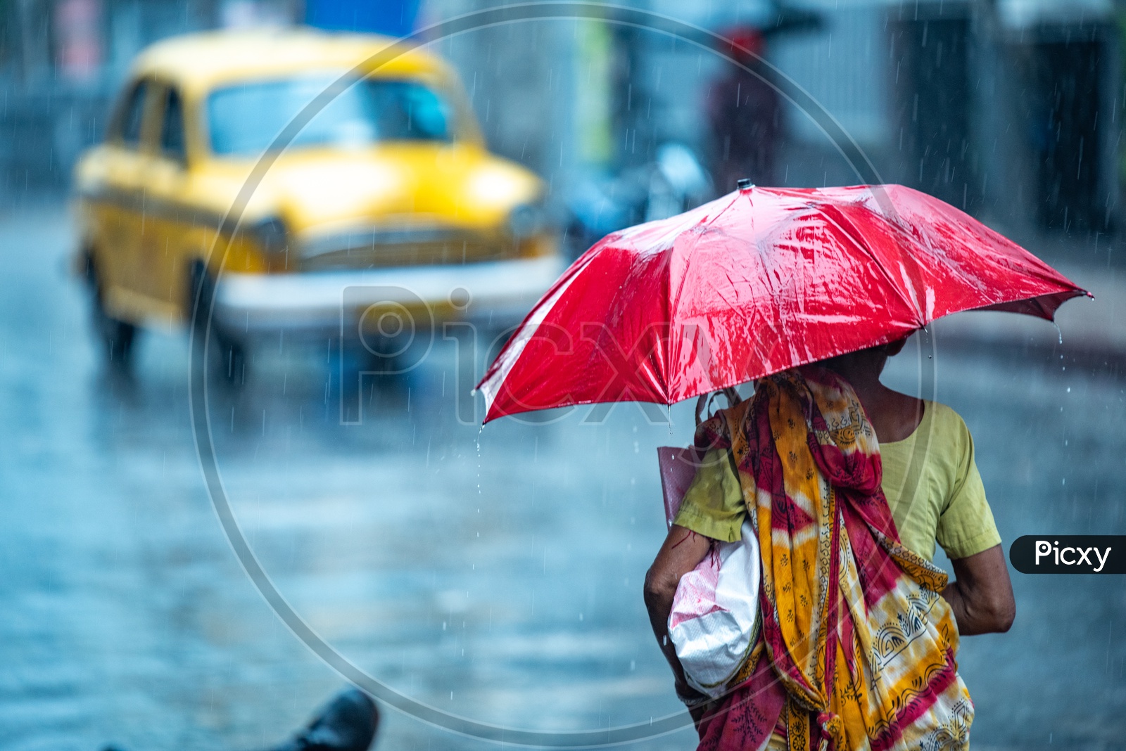 A woman walks holding an umbrella to cover herself from getting drenched as it rains heavily in Howrah,Kolkata.