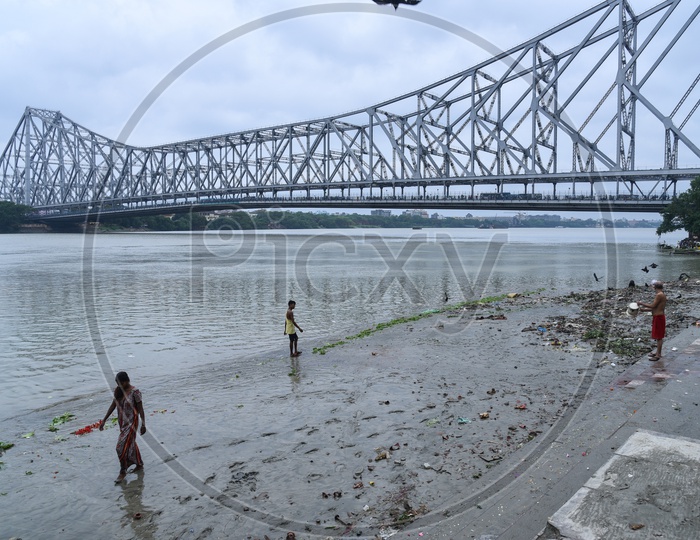 Local People At The Bank Of Hooghly River with  Howrah Bridge   In Background