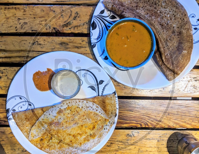 Egg dosa with chicken curry on a wooden table