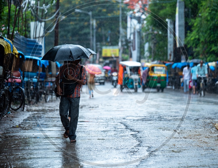 A  man Holding  a  Umbrella In Hand  and Walking On The Streets  in Heavy Rain In Kolkata