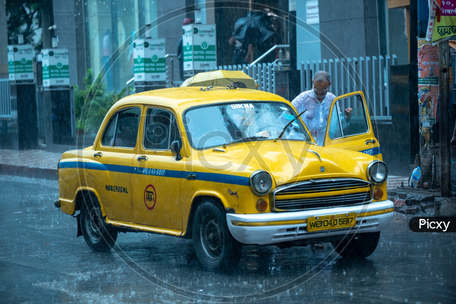 A Commuter Taking  a  Yellow Cabs Or taxis   in Heavy Rain Due To Cyclone Fani