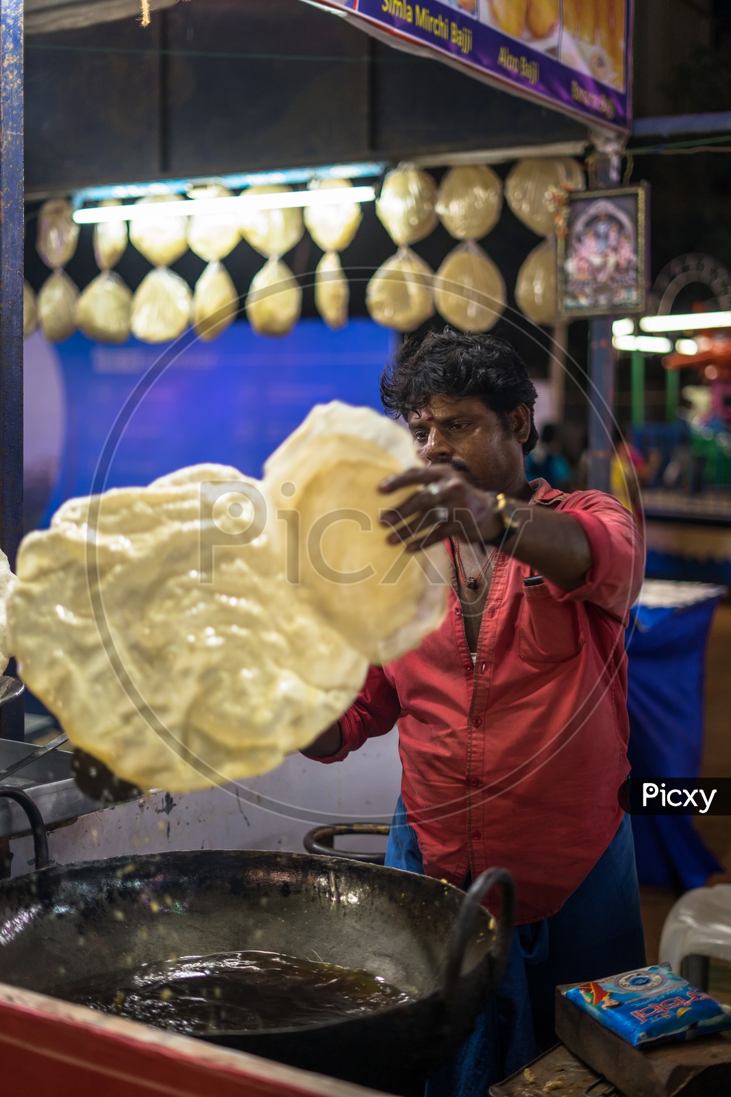 A man making large apadam in the food stall