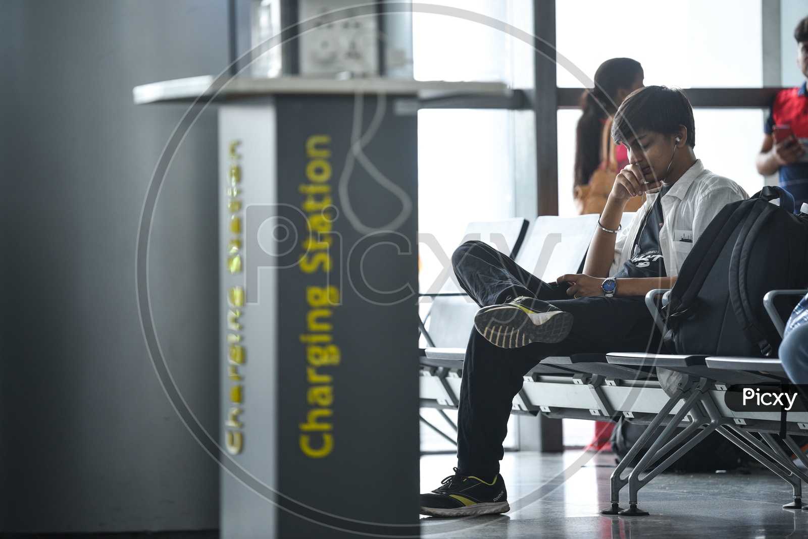 A Young Man  Watching Something In His Smart Phone  By Waiting In  A Waiting Lounge  At  Airport