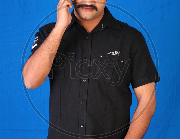 An Indian Man Speaking In a Mobile Phone On an Isolated Blue Background eaking In a Mobile Phone On an Isolated Blue Background