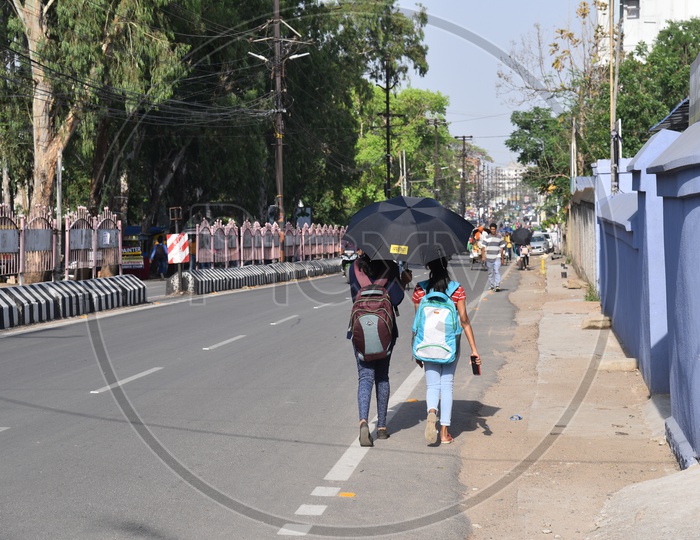 College Girls  Walking On The Road By Using Umbrella  to take Shade From Bright Sun On Dr Camil Bulcke Road  in Ranchi