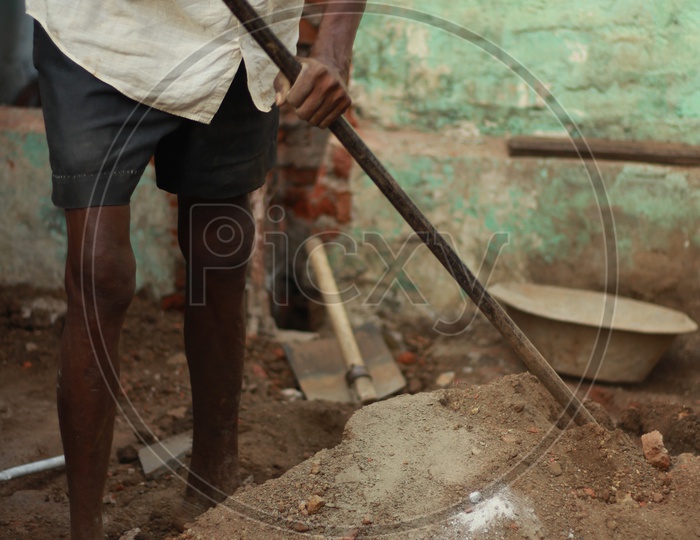 Indian Man digging mud with Iron Crowbar