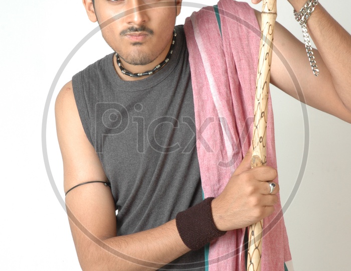 An Indian  Man  In Traditional Rural Man Attire  Holding  Wooden Stick in Hand  and Posing On an Isolated White Background
