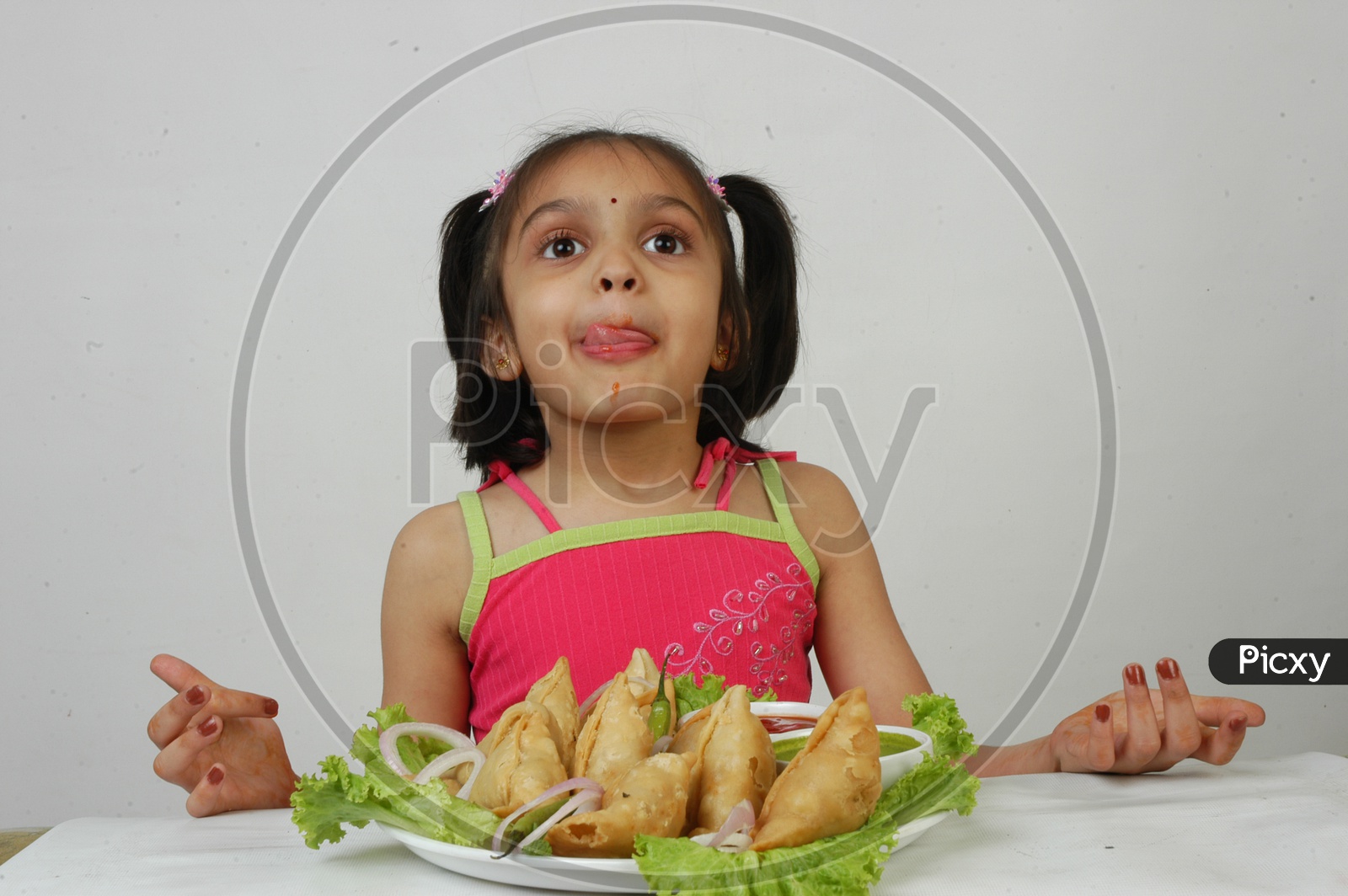 An Indian  Girl Kid At Samosas Plate With an Expression on an Isolated White Background