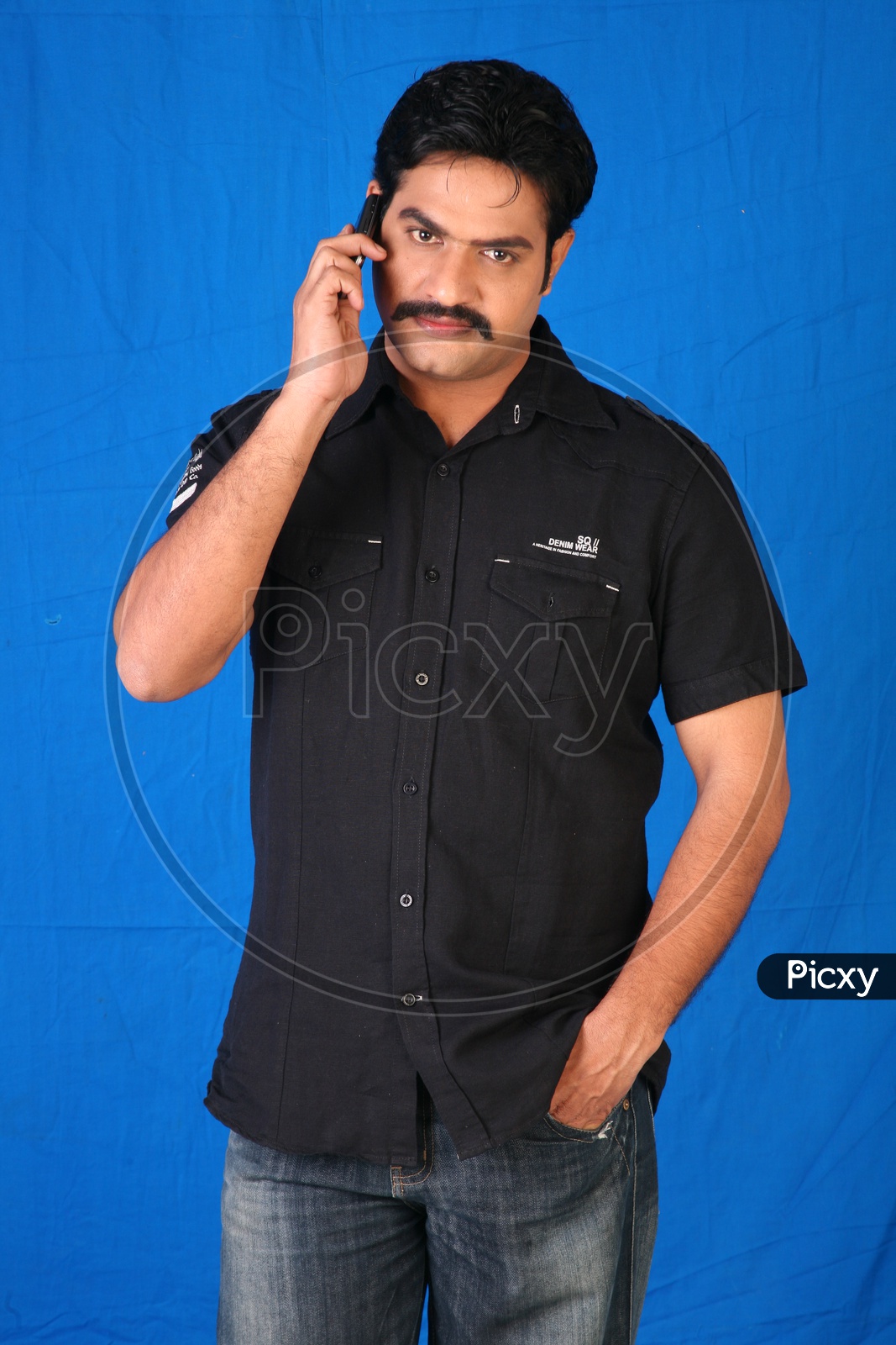 An Indian Man Speaking In a Mobile Phone On an Isolated Blue Background