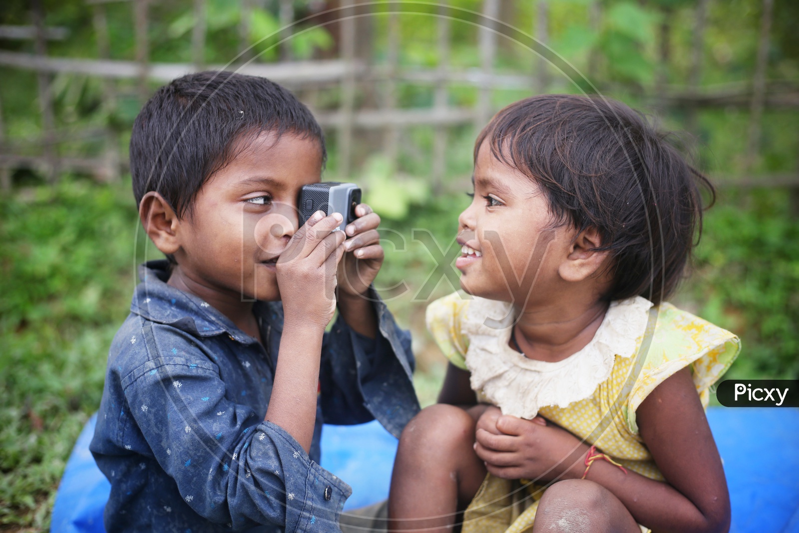 Indian Rural Village Children ( Siblings )  Having Fun With A GoPro Action Camera With a  Smiles On Their  Faces