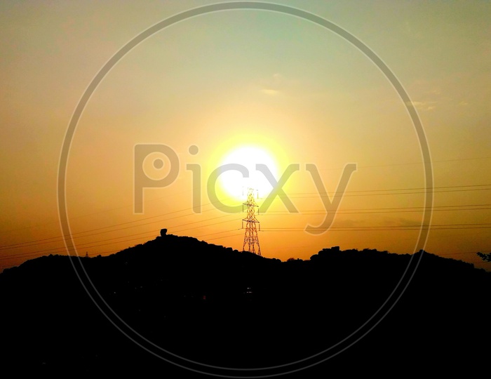 Silhouette Of High Tension Electricity Poles Over Sunset Sky Background
