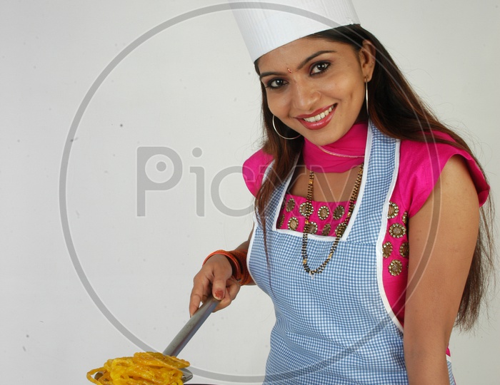 An Indian Woman Wearing Kitchen Apron And Cooking Jalebi Or Jilebi  Sweet On an Isolated White Background