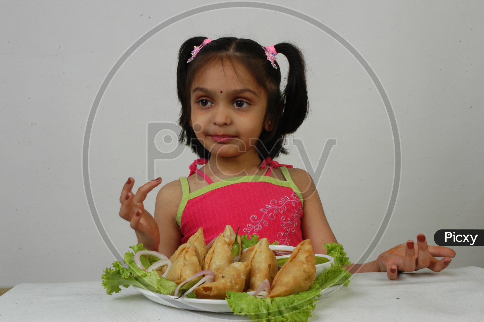 An Indian  Girl Kid At Samosas Plate With an Expression on an Isolated White Background