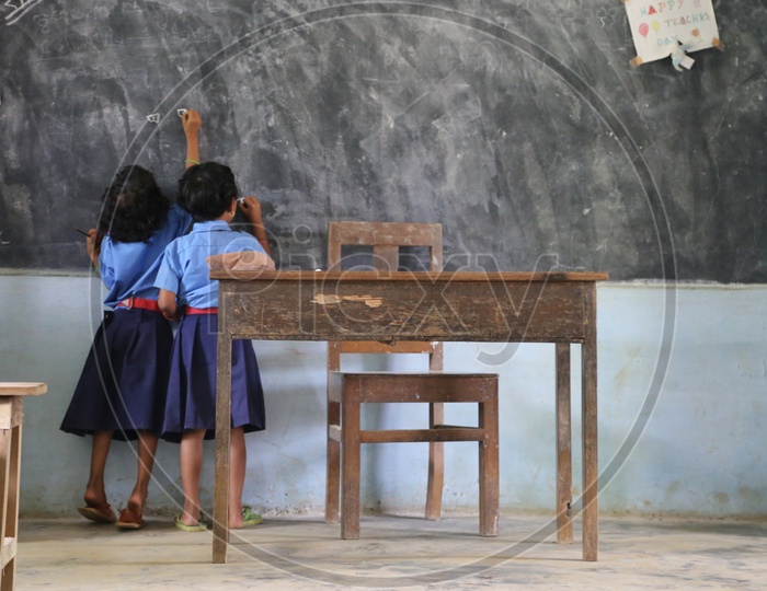 Girl Child Students Writing On Blackboard in a School Classroom