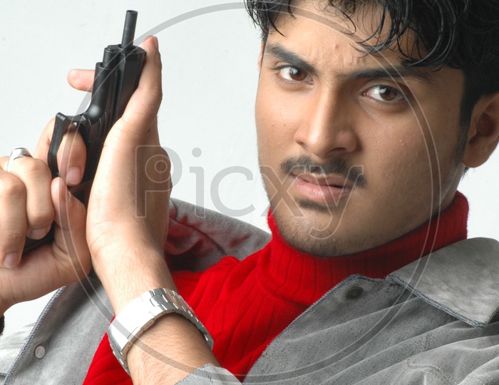 A Young Indian Man Holding Gun or Pistol  And  Posing  On an Isolated White Background