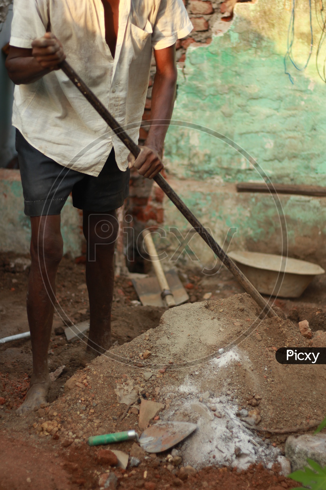 Indian Man digging mud with Iron Crowbar
