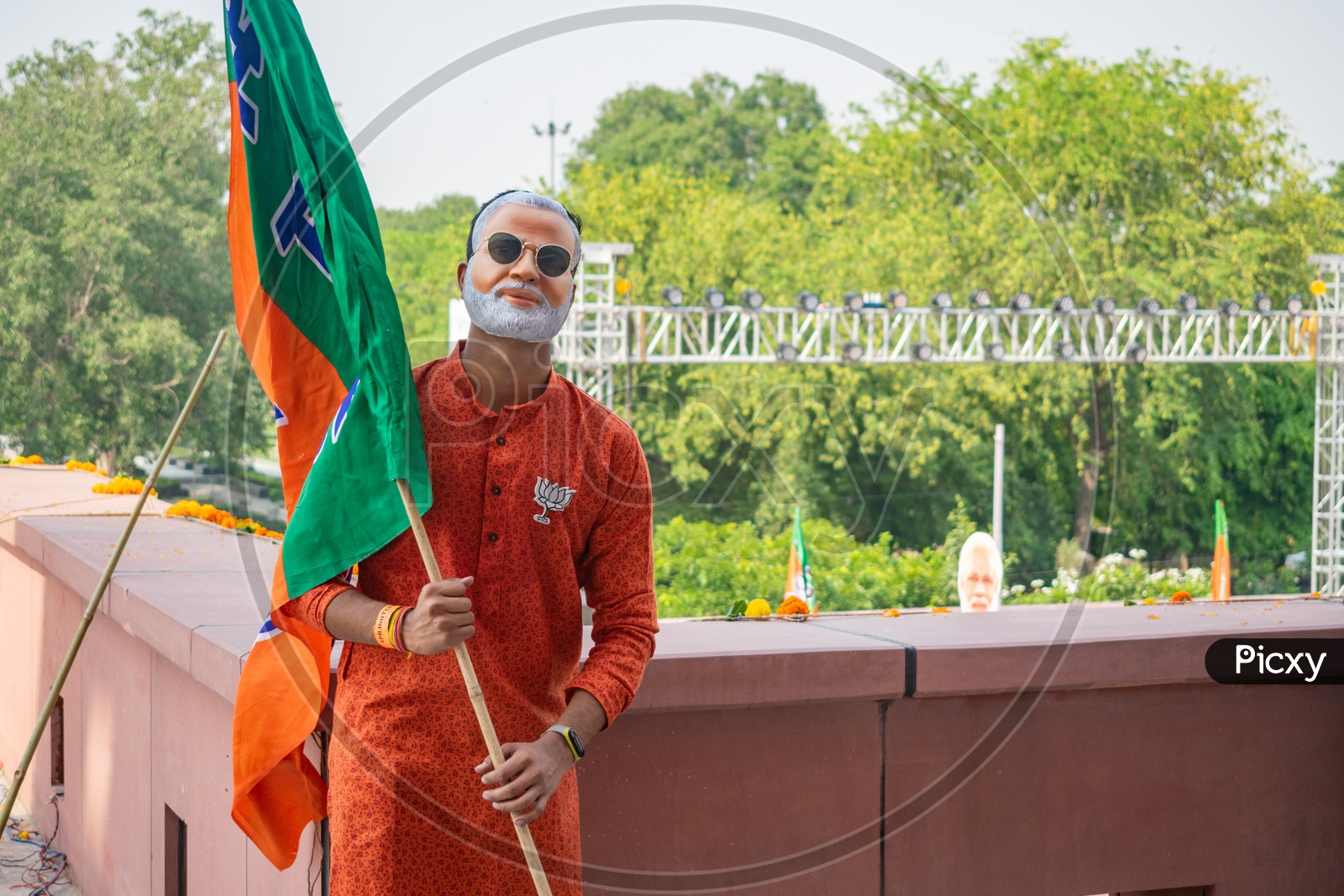 A man wearing mask of Narendra Modi and holding flags of Bhartiya Janta Party(BJP)