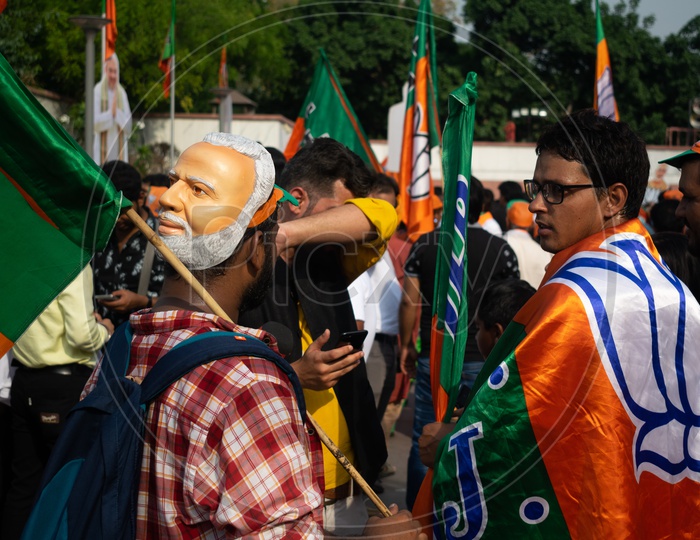 A man wearing mask of Narendra Modi and others holding flags of Bhartiya Janta Party(BJP)