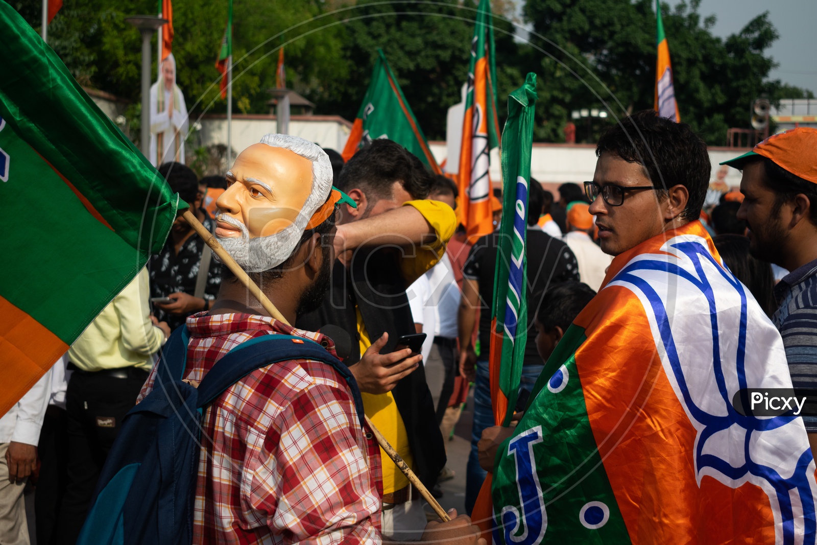 A man wearing mask of Narendra Modi and others holding flags of Bhartiya Janta Party(BJP)