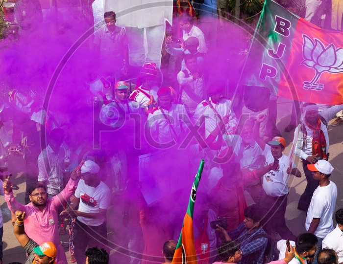 People using color smoke cans and holing flags of Bhartiya Janta Party(BJP)