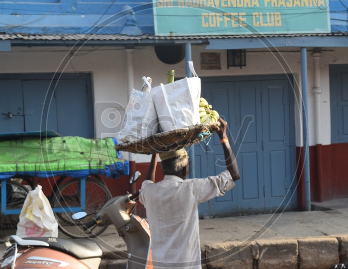 A Street Vendor Carrying Bananas In a Basket On His Over Head In  KR Market