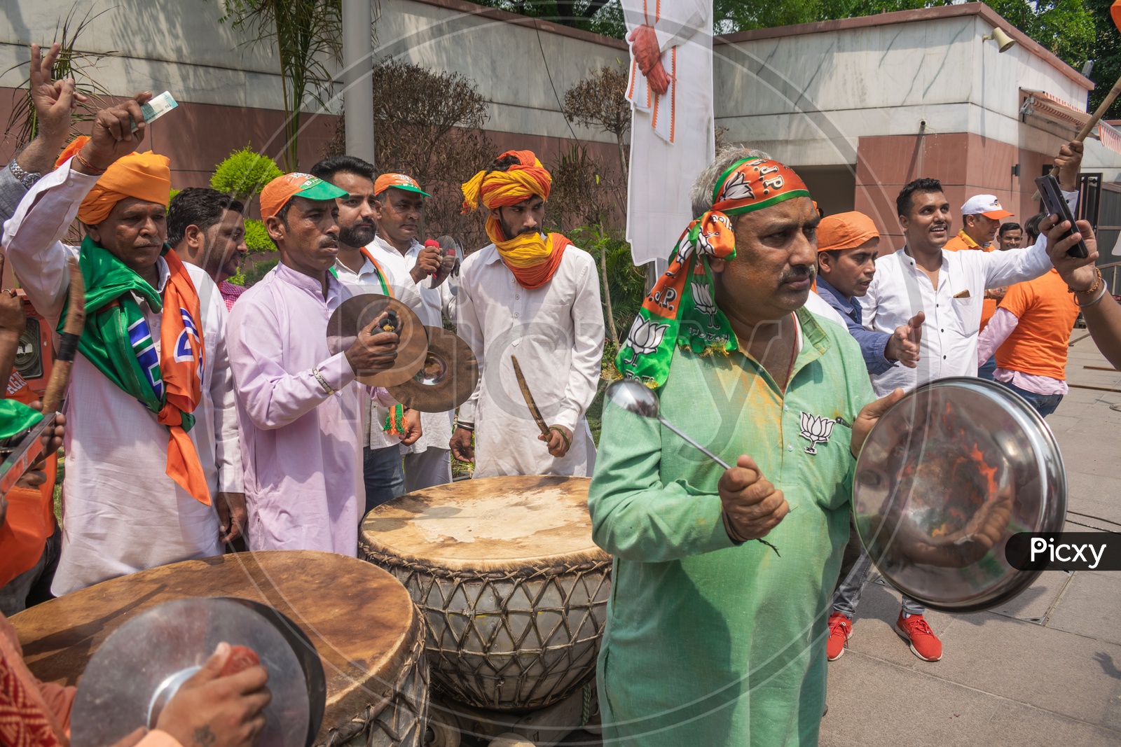 Men playing cymbals (Jhanj-manjira) and drums(Nagada) and a man making a sound with plate at the occasion of Bhartiya Janta Party(BJP) victory