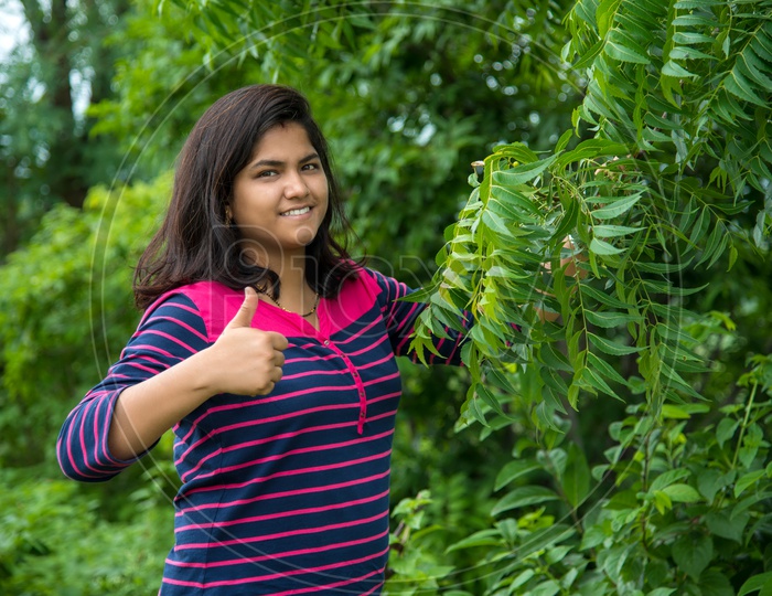 A Young Indian Woman Or Agricultural Student or Botany Student Inspecting or examining Neem Leafs or  Azadirachta  Indica   Or  Indian Lilac   Leafs On a Tree