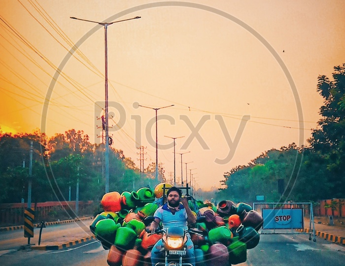 Indian man Carrying Pile Of Plastic Water Vessels In Bike on Indian Roads