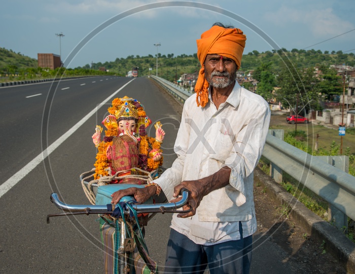 An Old Man Or Hindu Devotee  Taking The Lord  Ganesh Statue  on His Bicycle  Back  For    Visarjan Or Nimarjan  During  Ganesh Chathhurdhi  Festival