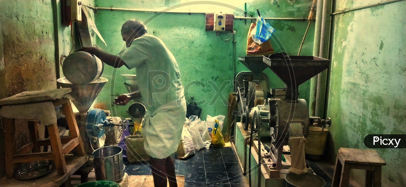 An old man working relentlessly in his flour grinding shop at night