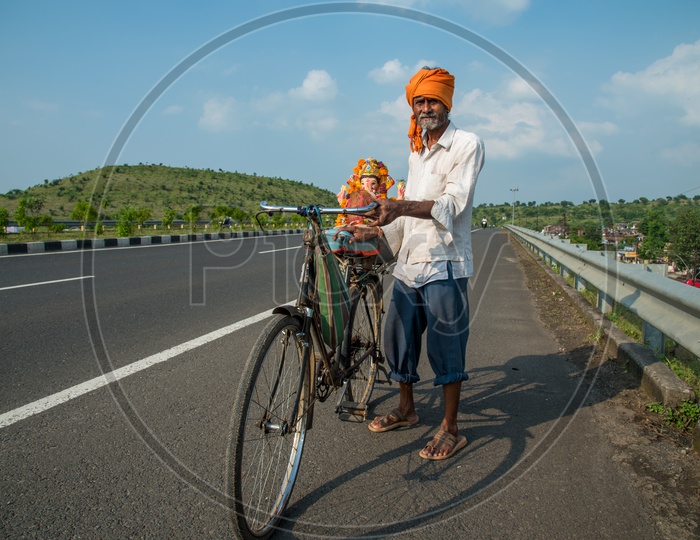 An Old Man Or Hindu Devotee  Taking The Lord  Ganesh Statue  on His Bicycle  Back  For    Visarjan Or Nimarjan  During  Ganesh Chathhurdhi  Festival