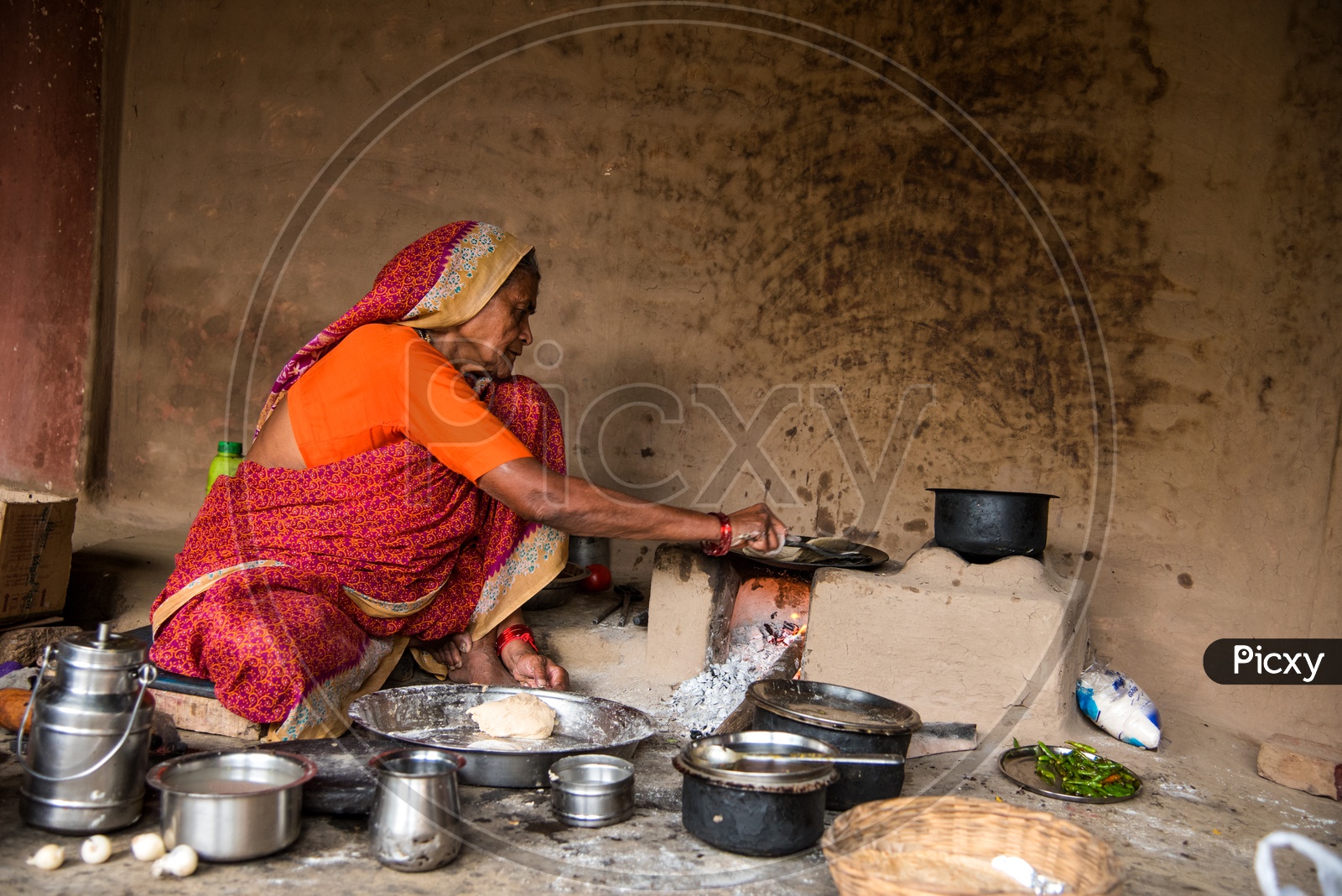Image Of An Indian Old Woman Making Or Cooking Food In An Ancient Or Old Kitchen With Earthen