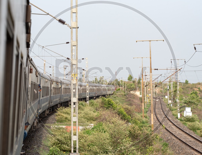Indian Railways train On Track With a View Of Electricity Poles And Adjacent track