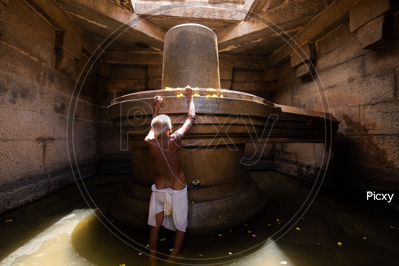 A Priest  Performing  Pooja For the Badavi Linga Statue  Surrounded By  A Pool Of Water In An Ancient Temple In Hampi