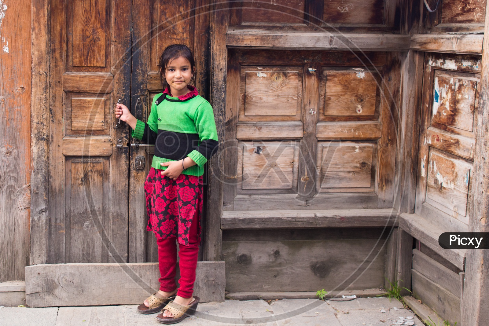 A Girl Standing at a Door Step of a House In A Village