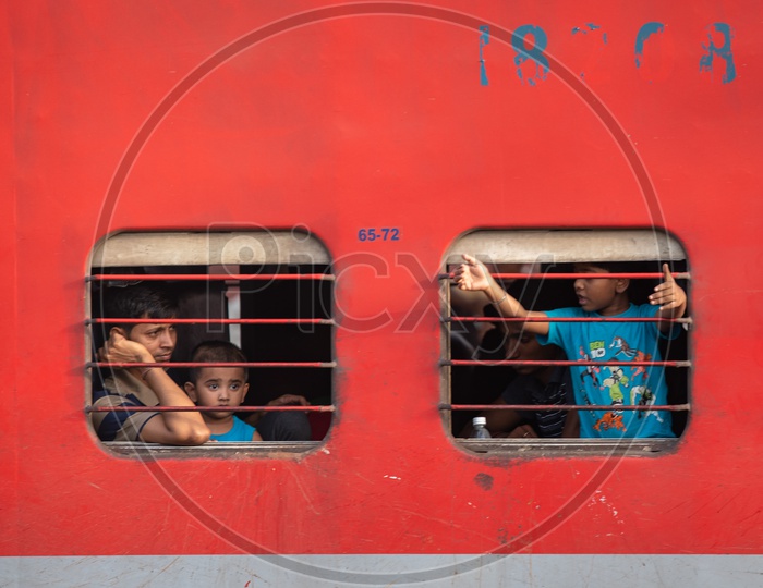 Indian Children Sitting At a train Window Seat And Looking Through The Window  In an Indan Railway Train Coach Or Bogie
