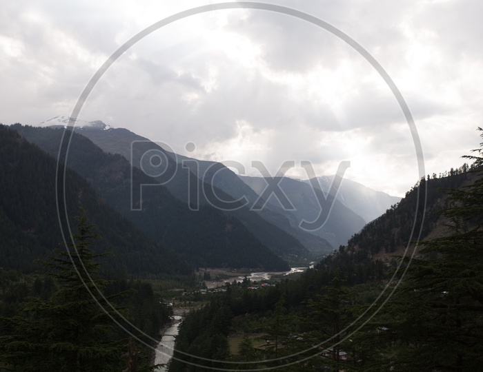 Landscape Views With Snow Capped Mountains And Cotton  fog Clouds And Green Terrain Hills on the River Valleys