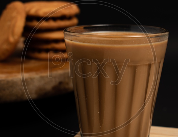 Aromatic beverage Tea/chai   with Good-day biscuits placed on wooden plates on a black background.