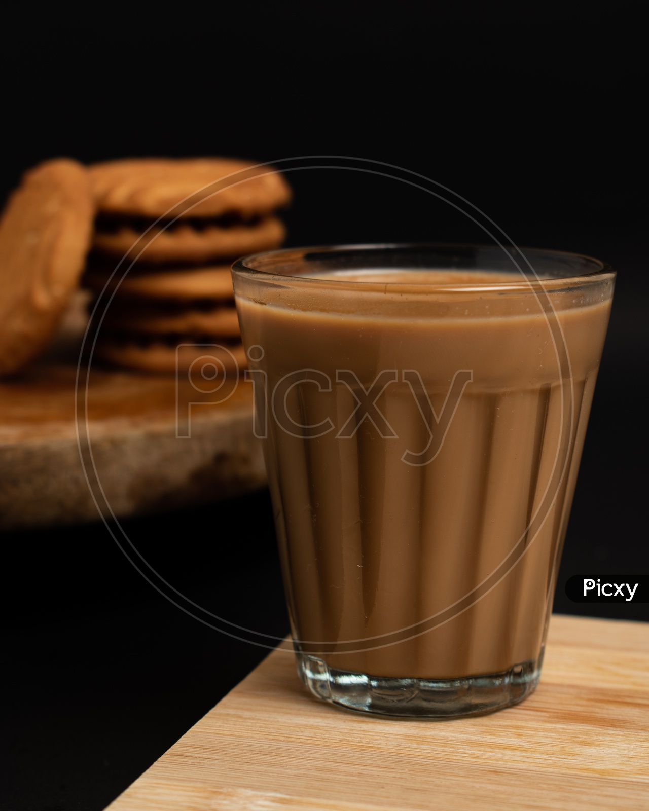 Aromatic beverage Tea/chai   with Good-day biscuits placed on wooden plates on a black background.