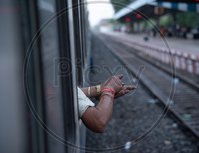 A  Man Put His hands Out Of a Train Window for Mixing Gutkah or Pan Masal Or Tobbaco