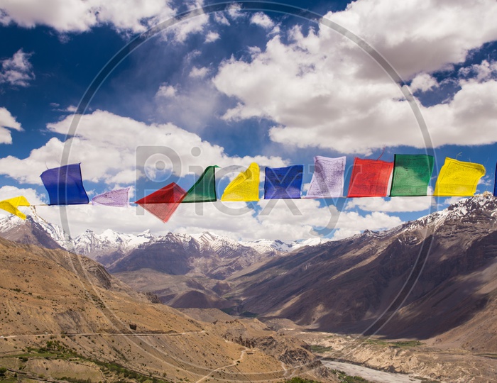 Colorful Tibetan Flags With a View Of Snow Capped Mountains And Sedimentary Hills On The Background