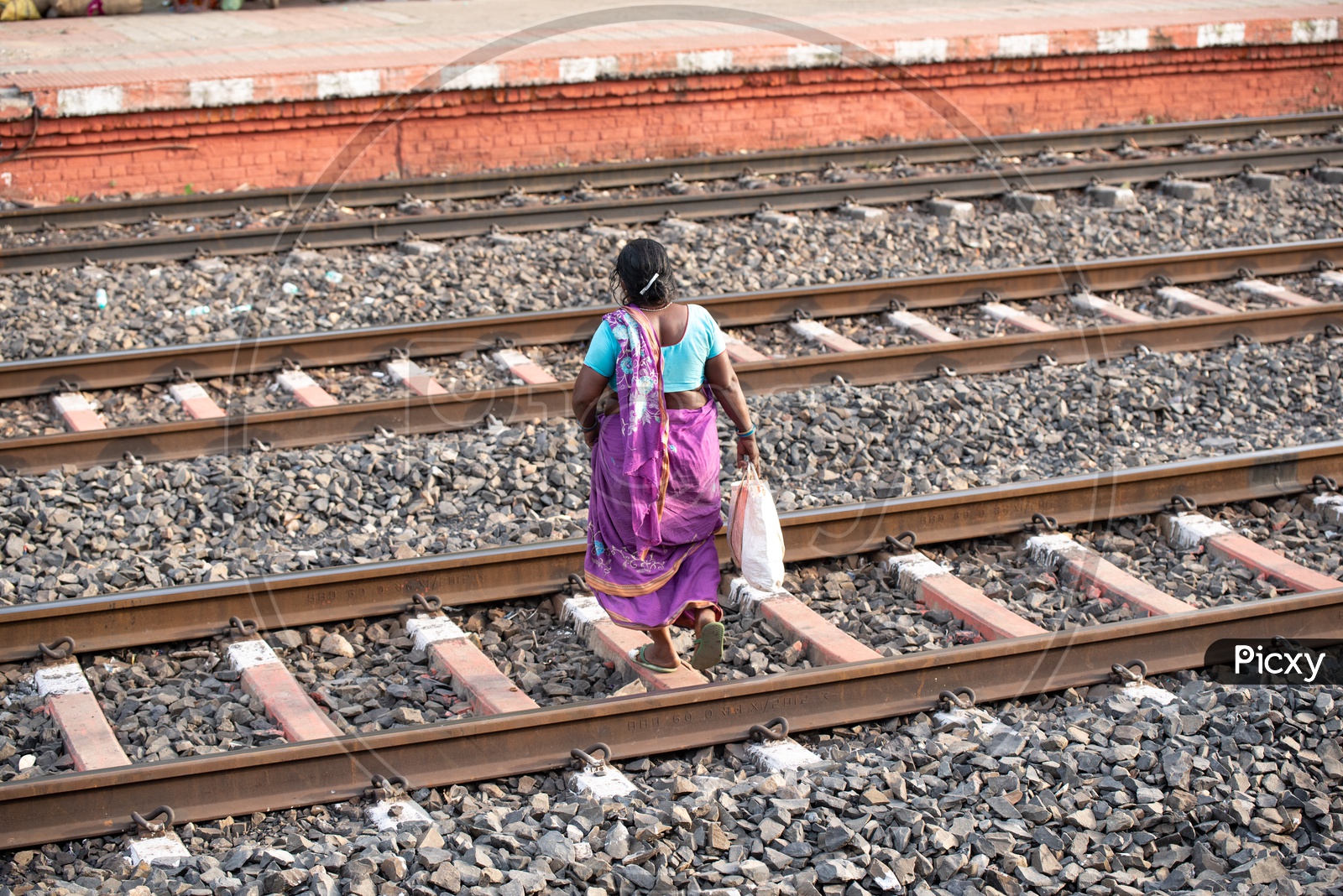 An Indian Woman Or Passenger  Crossing the railway Tracks At a Railway Station