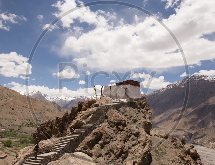 Hindu Temples On The Terrains With Sedimentary Hills and Cotton Candy Clouds In Background  in Spiti Valley