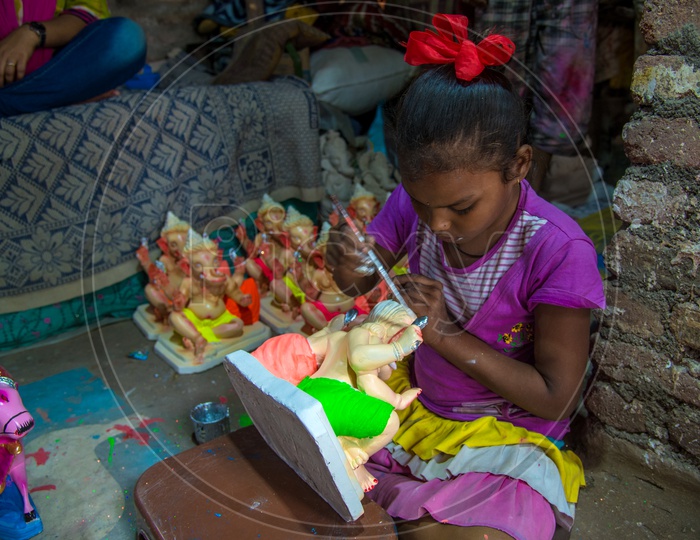 A Small Girl Or Child  Working In Ganesh Idols Making Workshop Painting The Ganesh Idols