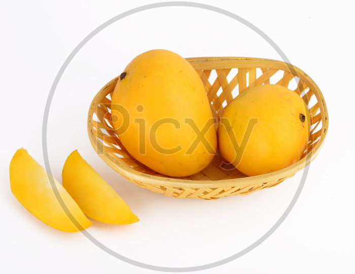 Fresh Ripen Mangoes And Mango Slices In a Wooden Weaved Basket  on an Isolated White  Background