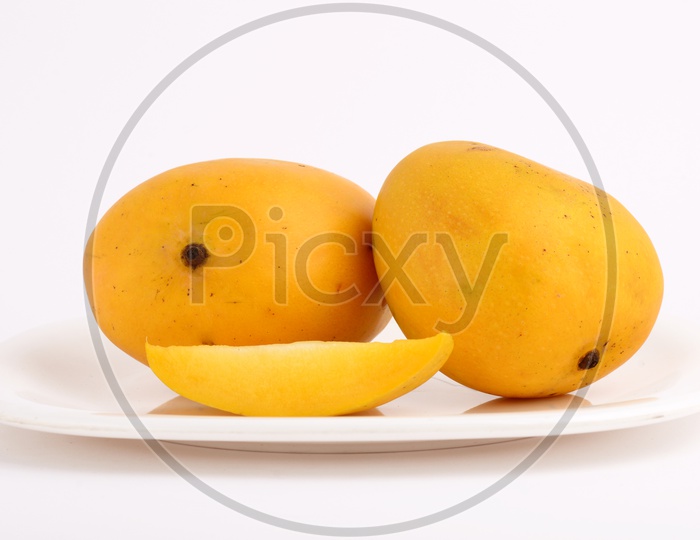 Fresh Ripen Mangoes And Mango Slices On A White Plate On an Isolated White Background