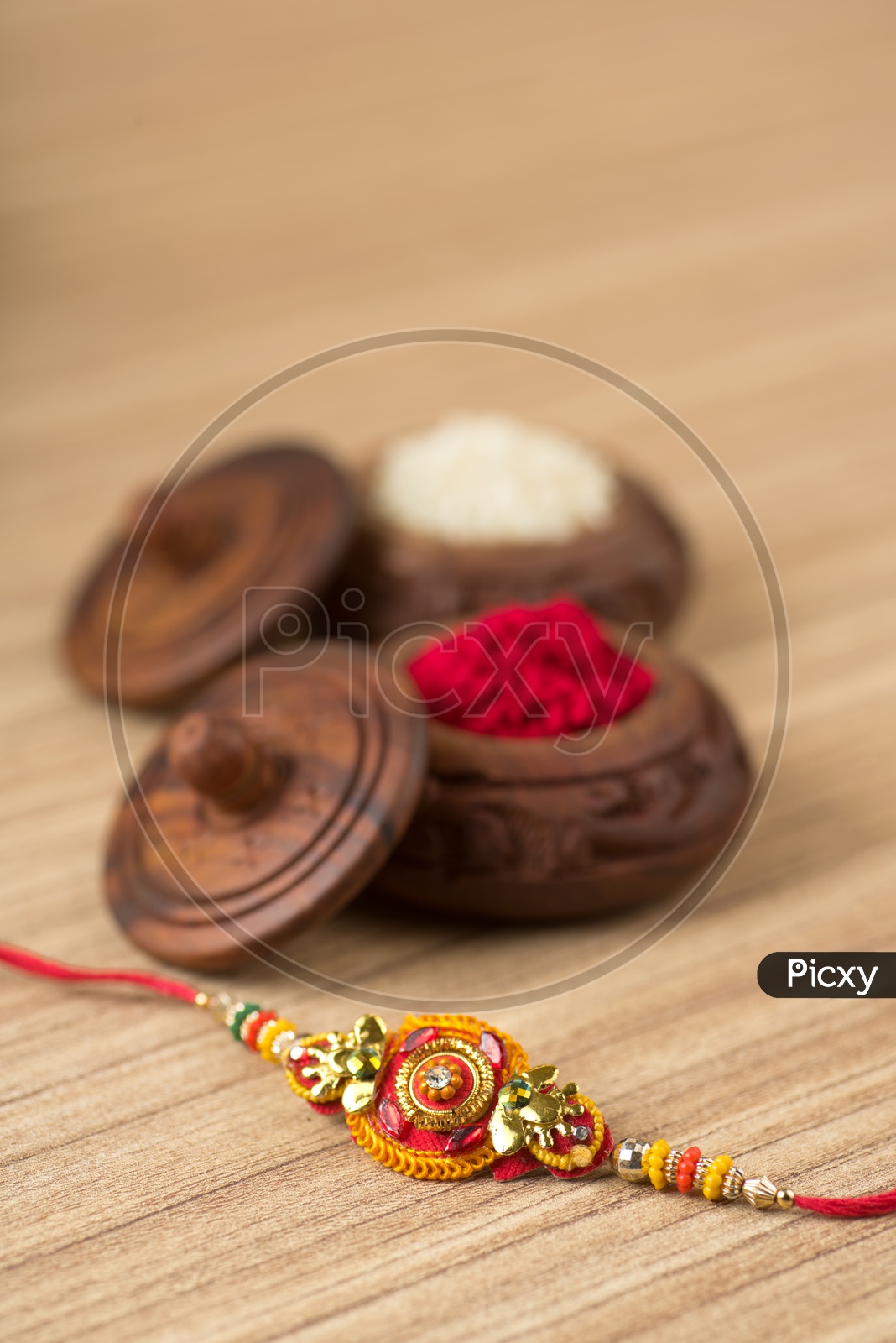 An Elegant Rakhi With Kumkum And Rice Grains On an Isolated Wooden Background